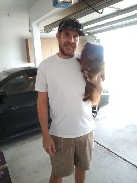 The groomer holding a freshly groomed pup